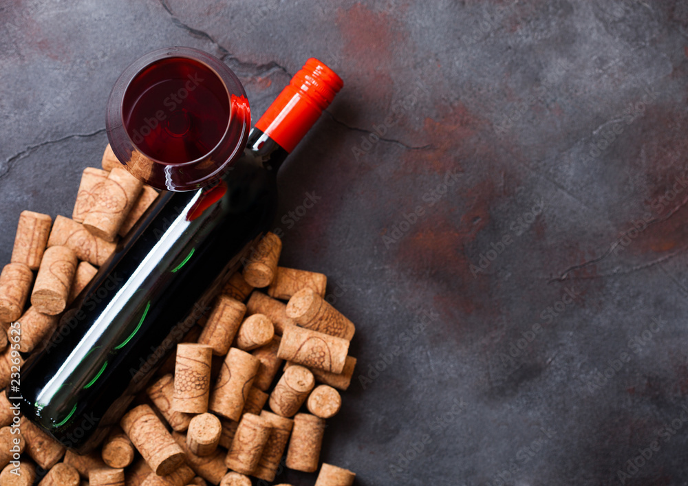 Elegant glass and bottle of red wine with corks on stone kitchen table background. Top view. Space for text
