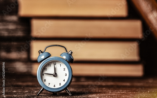 Alarm clock and books on wooden table and background