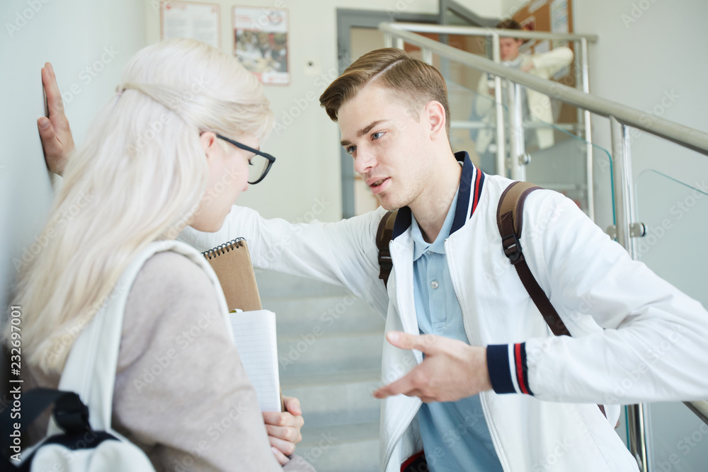 Obraz premium Casual guy trying to get acquainted with the girl he likes by staircase in college