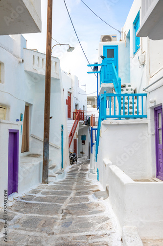 Traditional houses with blue doors and windows in the narrow streets of greek village in Mykonos, Greece © dtatiana