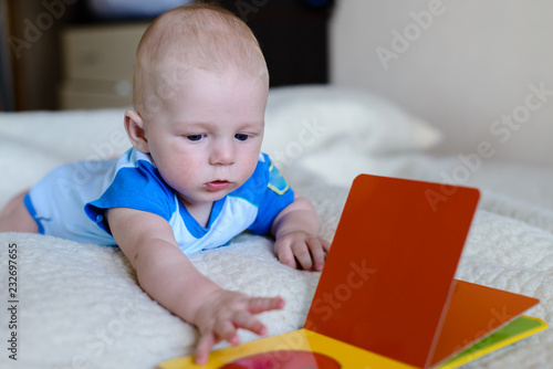 baby boy lying reading a children's book