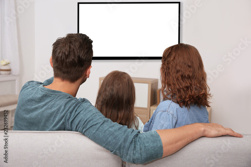 Family watching TV in room at home