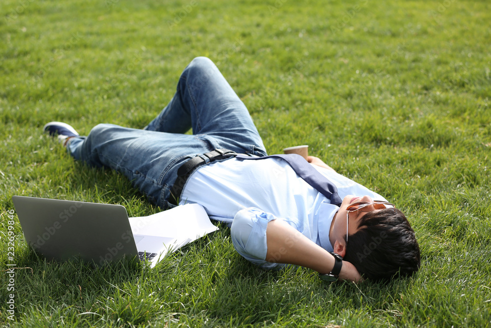 Young man lying on green lawn in park. Joy in moment Young man lying on green lawn in park. Joy in moment