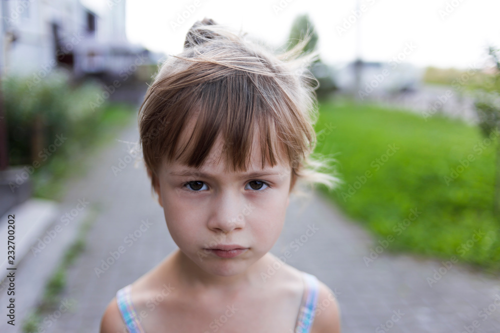 Φωτογραφία Close-up portrait of pretty young little blond pale unhappy moody friendless child girl looking sadly in camera on blurred sunny outdoors background