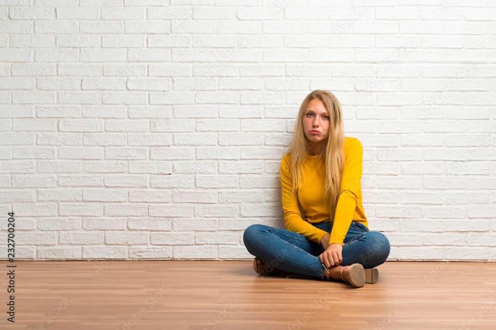 Young girl sitting on the floor with sad and depressed expression. Serious gesture Young girl sitting on the floor with sad and depressed expression. Serious gesture