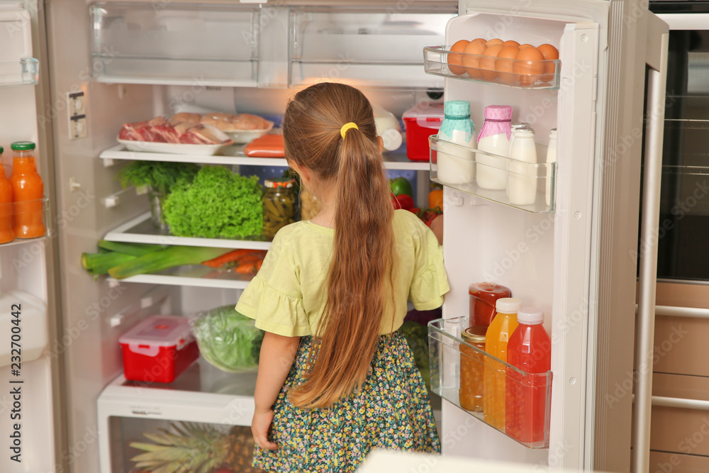 Cute little girl choosing food in refrigerator at home Cute little girl choosing food in refrigerator at home