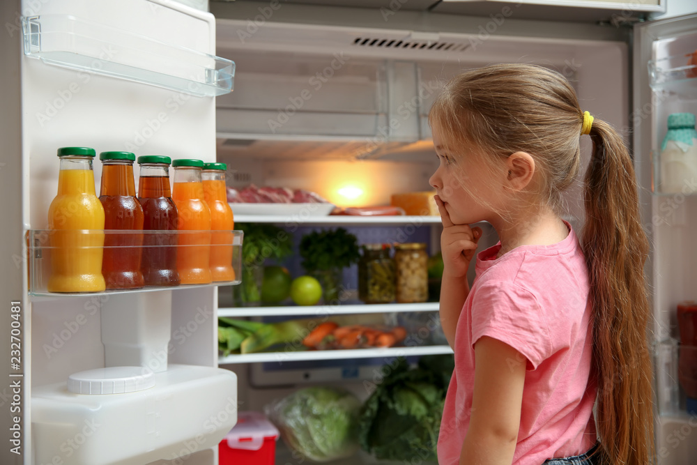 Cute little girl choosing food in refrigerator at home Cute little girl choosing food in refrigerator at home