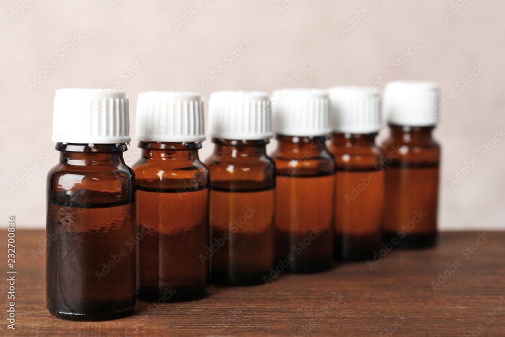 Glass bottles with essential oil on wooden table Glass bottles with essential oil on wooden table