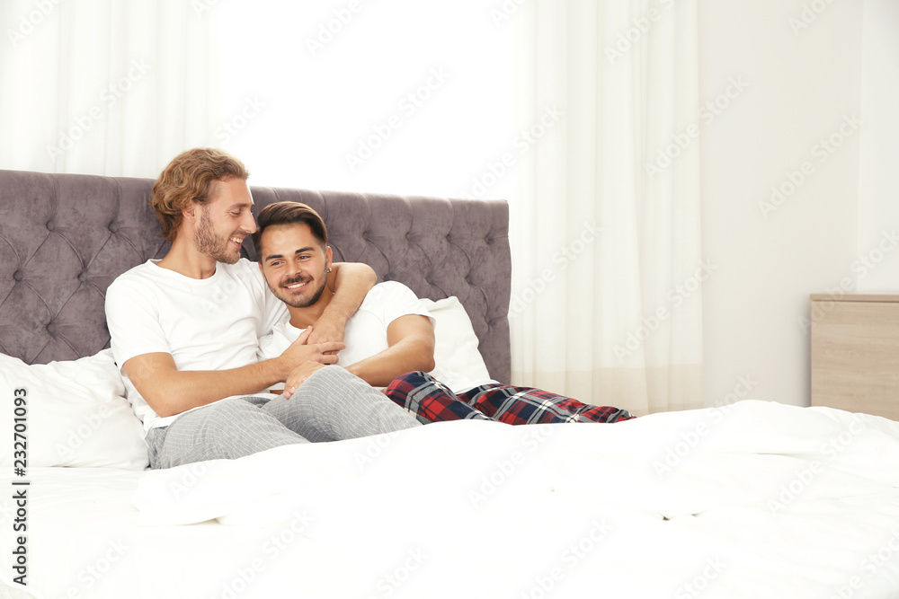 Happy gay couple on bed at home
