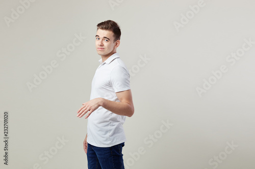 Billede på lærred Indifferent  guy dressed in a white t-shirt and jeans is on a white background i