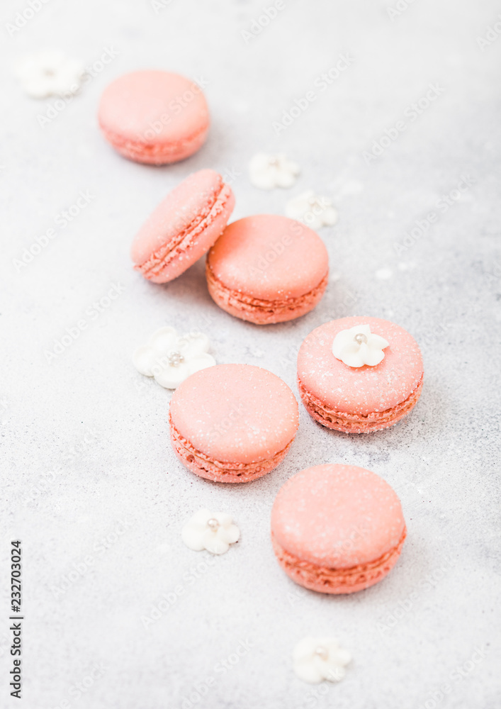 Pink dessert cake macaron or macaroon with white sweet flowers on stone kitchen background. Top view Pink dessert cake macaron or macaroon with white sweet flowers on stone kitchen background. Top view