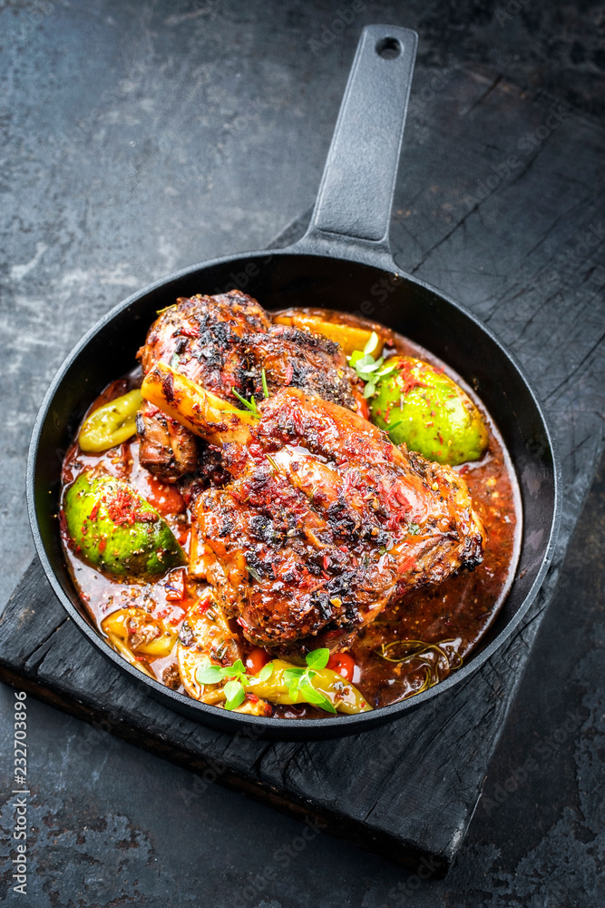 Traditional barbecue leg of lamb with lemon and tomatoes as closeup in a cast-iron skillet Traditional barbecue leg of lamb with lemon and tomatoes as closeup in a cast-iron skillet