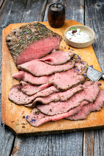 Traditional lunch meat with sliced cold cuts roast beef and remoulade as closeup on a cutting board