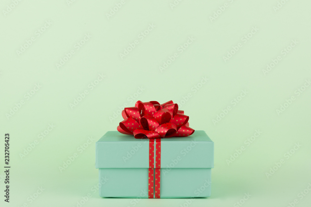 Fototapeta premium Gift Box, Pastel Green gift box with Red ribbon and bow on light green background, isolated on Pastel Colors, copy space