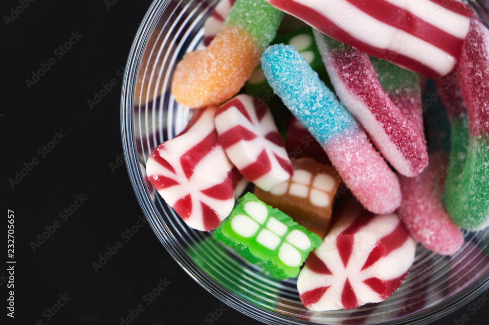 Fototapeta premium Various colorful candies / sweets, gum drops in a glass on black background
