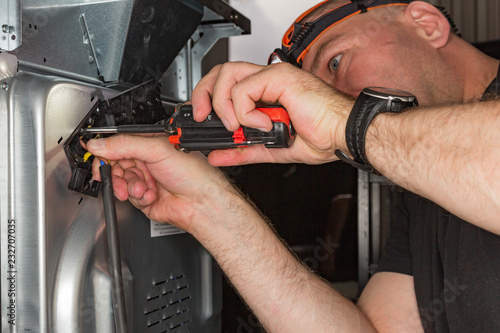 the image of the repair of household appliances, the worker is repairing the electric stove
