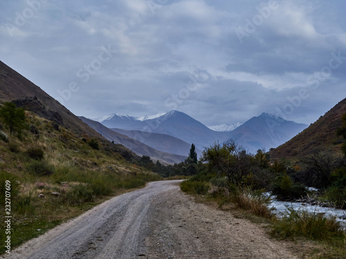 dirt road leading to high mountains passing along a mountain river