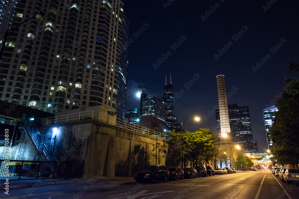 Chicago night street scene with a city tower, a smokestack, the 
