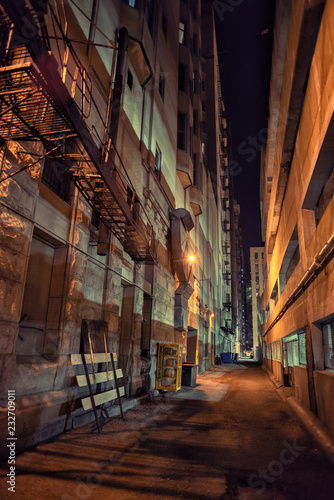 Dark and eerie downtown urban city alley with a fire escape next © Bruno Passigatti