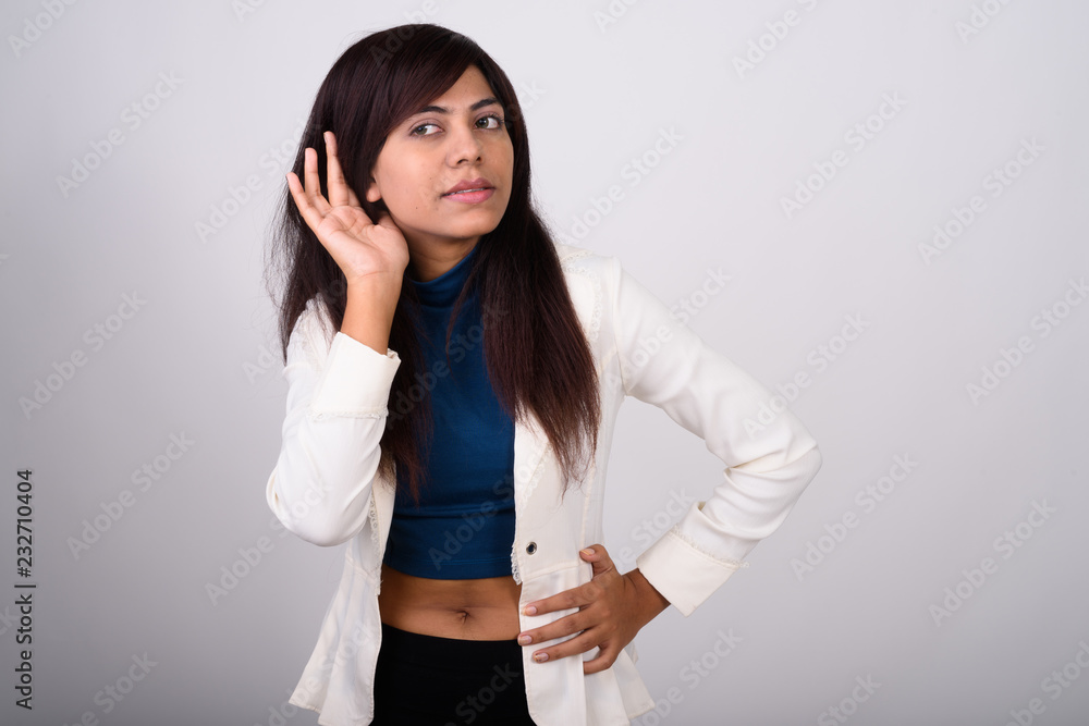 Studio shot of young Persian businesswoman thinking while listen Studio shot of young Persian businesswoman thinking while listen