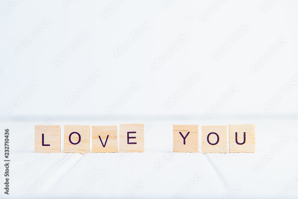 Message I love you spelled in wooden blocks standing on white wooden table. Valentines day background. Simplicity concept. Selective focus. Copy space. Message I love you spelled in wooden blocks standing on white wooden table. Valentines day background. Simplicity concept. Selective focus. Copy space.