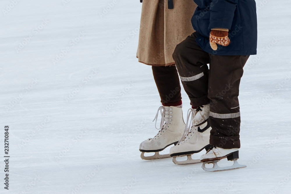 Mom teaches little son to ice skate. Unknowns boy with his mother ride on the ice rink Mom teaches little son to ice skate. Unknowns boy with his mother ride on the ice rink
