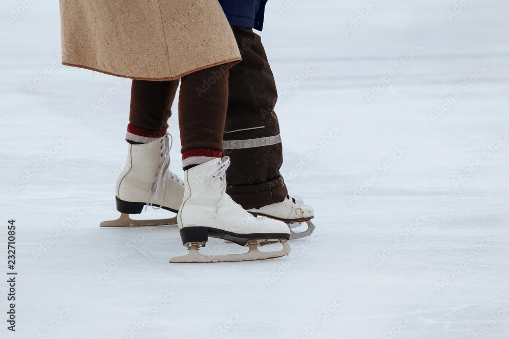 Mom teaches little son to ice skate. Unknowns boy with his mother ride on the ice rink Mom teaches little son to ice skate. Unknowns boy with his mother ride on the ice rink