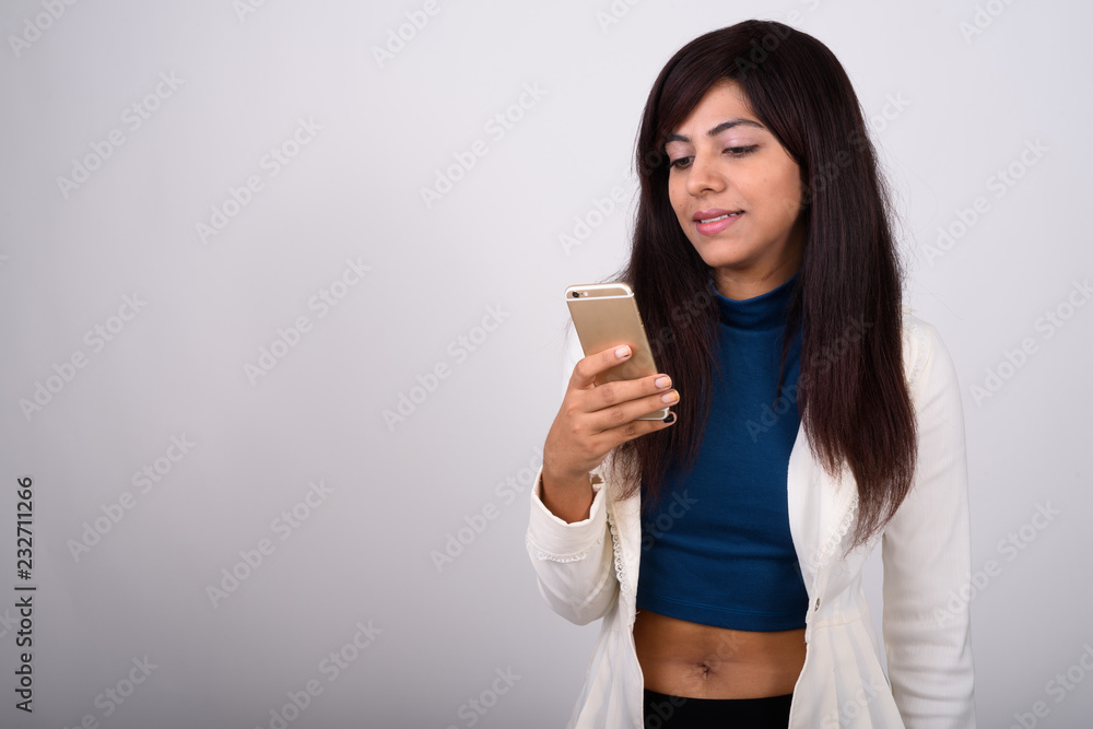 Studio shot of young happy Persian businesswoman smiling while u Studio shot of young happy Persian businesswoman smiling while u