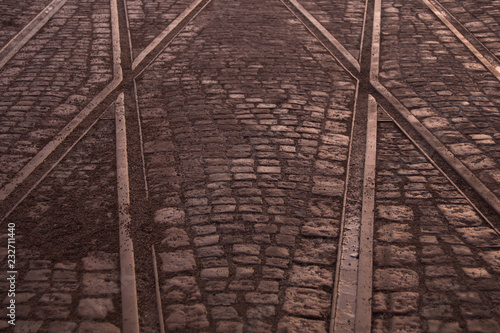 Crossing of tram rails on stone pavement in the city background
