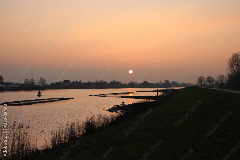 sunrise above the river Hollandsche IJssel at the village Nieuwerkerk in the Netherlands.