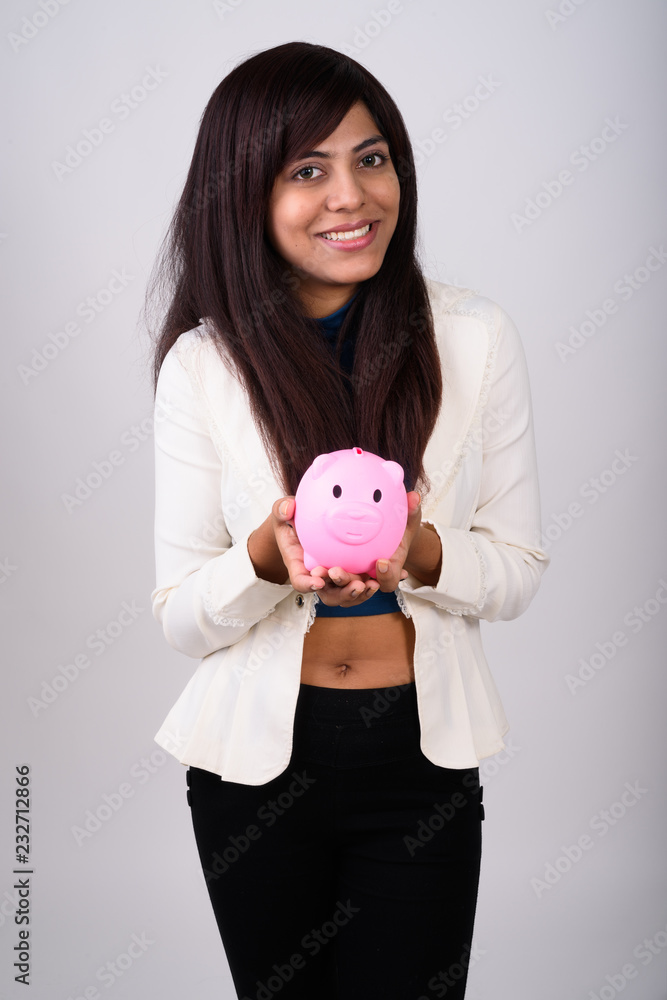 Studio shot of young happy Persian businesswoman smiling while h Studio shot of young happy Persian businesswoman smiling while h