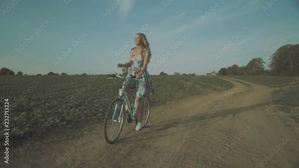 Beautiful girl riding a bicycle through a field in the countryside. Beautiful girl riding a bicycle through a field in the countryside.