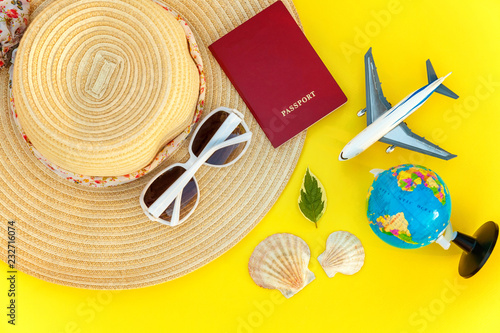 Flat Lay with hat, plane, passport, globe and sunglasses on yellow colourful trendy modern fashion background. Vacation travel summer weekend sea adventure trip concept