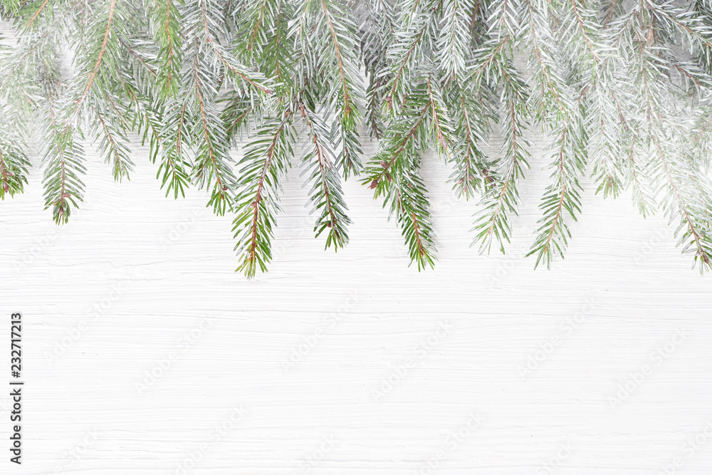 Obraz premium Christmas fir tree branches with snow on white wooden background. Copy space, top view