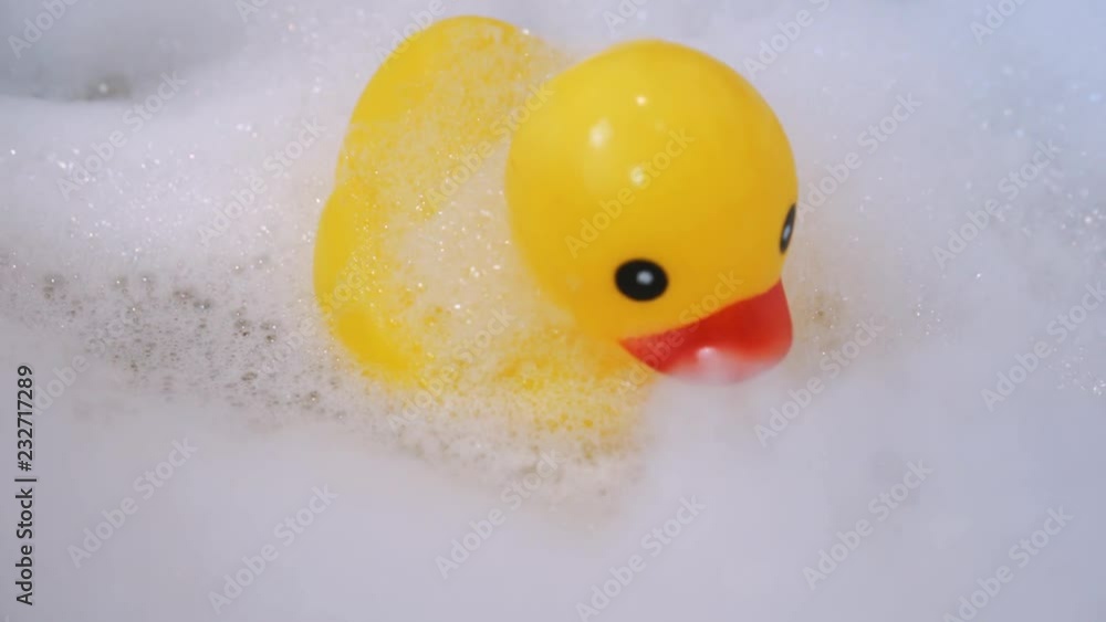 One yellow rubber duck with soap bubble bath, light background with bubbles. Kids spa concept. Children`s bath time concept. One yellow rubber duck with soap bubble bath, light background with bubbles. Kids spa concept. Children`s bath time concept.