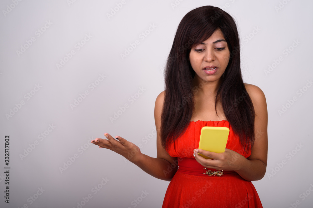 Studio shot of young Persian woman using mobile phone while look Studio shot of young Persian woman using mobile phone while look