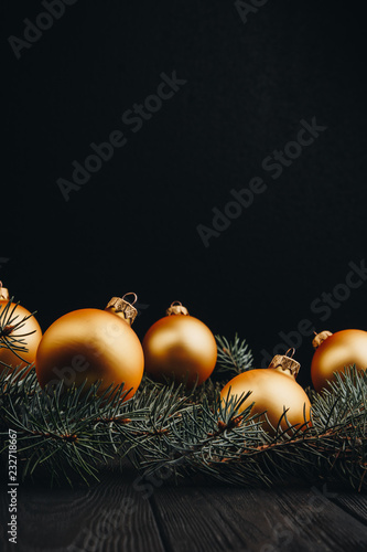 Christmas or New Year toy decorations golden balls and fur tree branch rustic on wooden background, top view, copy space