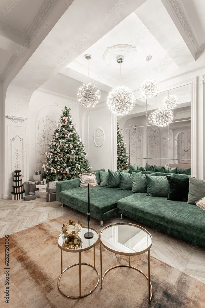 Christmas evening. classic luxurious apartments with decorated christmas tree. Living hall large mirror, green sofa, high windows, columns and stucco.