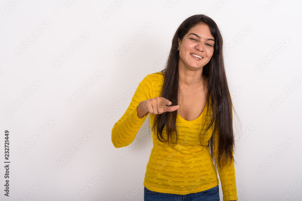 Studio shot of young happy Indian woman smiling while winking an Studio shot of young happy Indian woman smiling while winking an