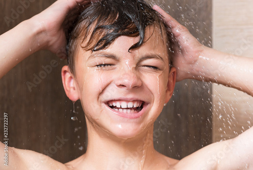 Happy boy washing head in shower in the bathroom - close up portrait