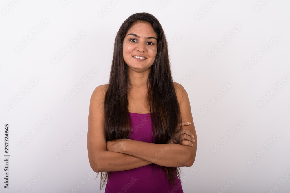 Studio shot of young happy Indian woman smiling while wearing sl Studio shot of young happy Indian woman smiling while wearing sl