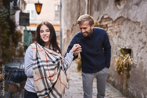 young romantic couple having fun during the city walk at the warm autumn day. man holding a woman's hand. Two lovers, man and young woman, are walking and laughing in Lviv, Ukraine photo