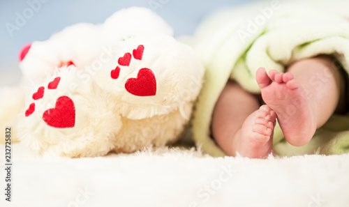 small tender legs of the baby, together with the paws of a Teddy bear with hearts on a white blanket ©  Даниил Дудник