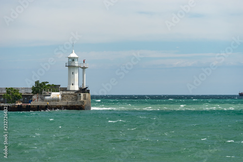 seascape with a white lighthouse on the horizon.