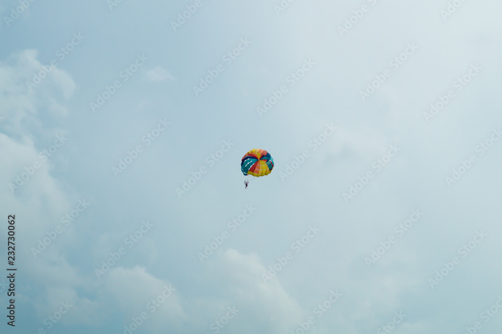 Skydiver flying with a colorful parachute on sky background Skydiver flying with a colorful parachute on sky background