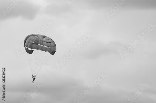 Skydiver flying with a parachute black and white background