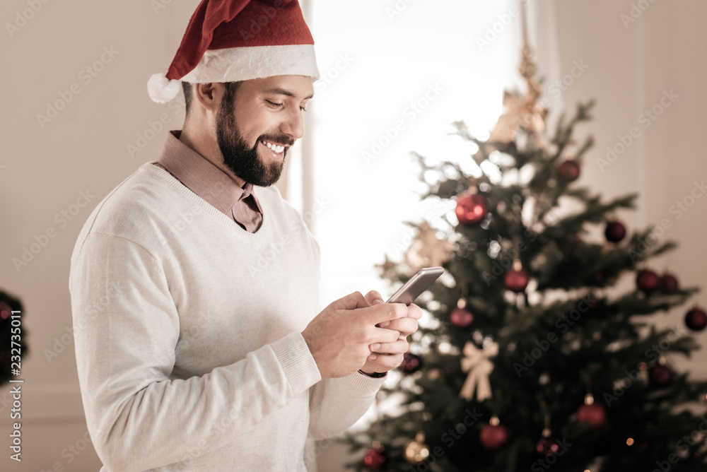 Good news. Handsome man standing in semi position and holding telephone in both hands while reading message Good news. Handsome man standing in semi position and holding telephone in both hands while reading message