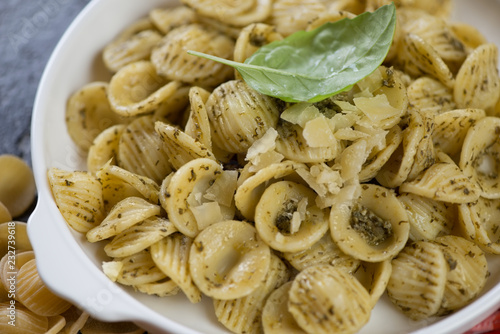 Closeup of orecchiette pasta with green basil pesto and grated parmesan, selective focus