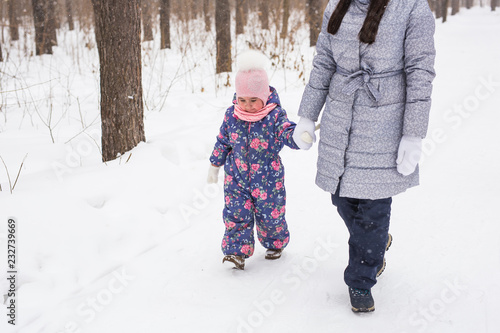 Winter, family and people concept - Close up of young mother is walking with her daughter in winter forest.