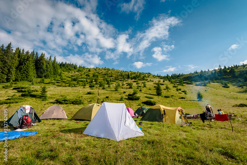 Tourist camp on green meadow in mountains on summer day